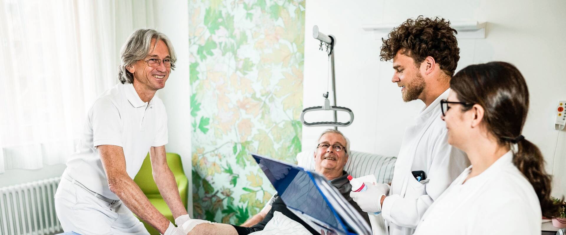 Glückliches medizinisches Personal am Bett eines Patienten