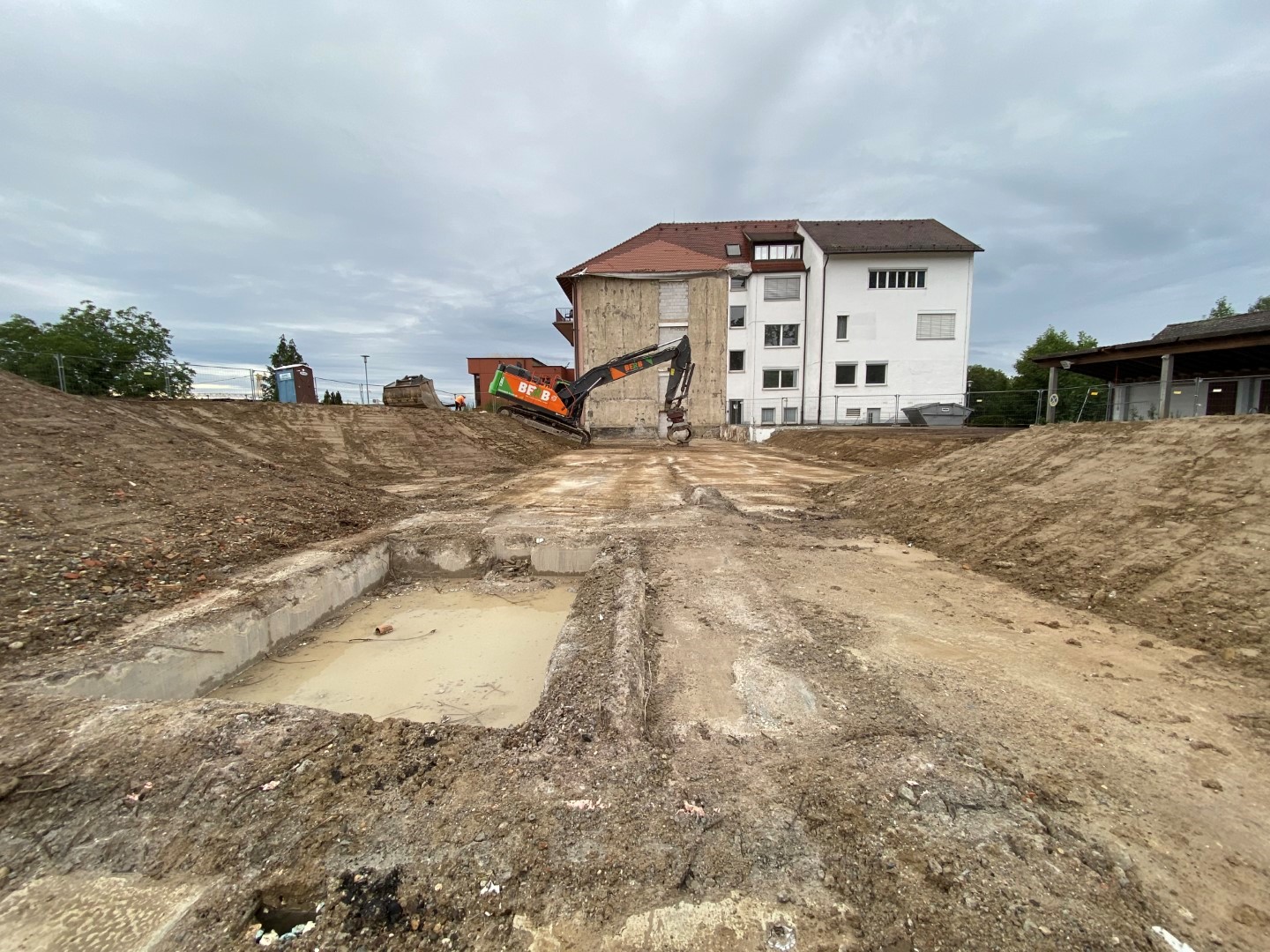 Blick auf das Abbruchgel&auml;nde mit dem erhaltenen Geb&auml;udeteil im Hintergrund.